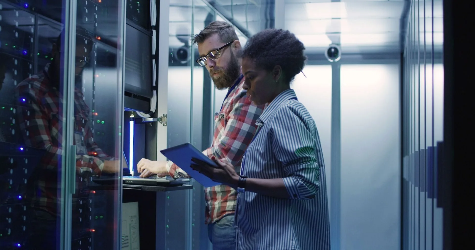 Technicians working between rows of server racks in a data centre