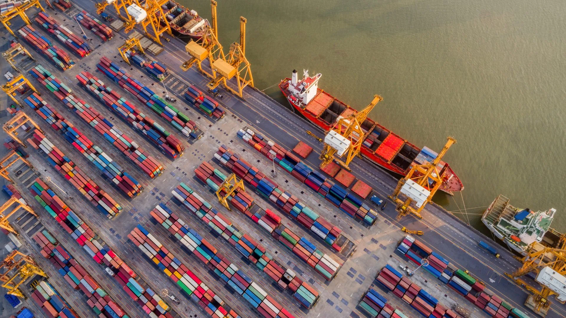 Overhead aerial of a container terminal, gantry cranes and stacked boxes